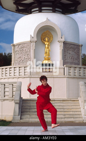 Carol Smith insegnante di Yoga facendo Surya Namaskar Sun Salutations davanti al Milton Keynes buddista Pagoda di pace Foto Stock