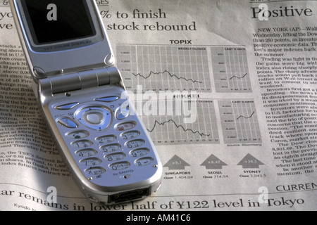 Telefono mobile sulla parte superiore della finanza e del business le pagine di un giornale quotidiano Foto Stock