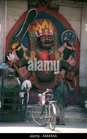 Immagine di Kala Bhairab a Kathmandu in Nepal e una donna in una bicicletta sorge nella parte anteriore di esso Foto Stock