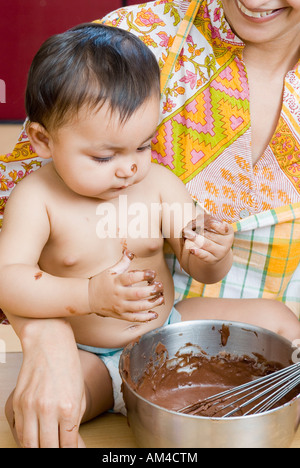 Close-up di una metà donna adulta con sua figlia mangiare in salsa di cioccolato Foto Stock