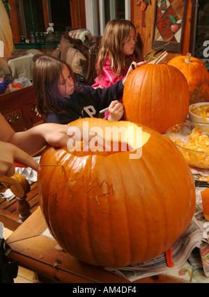 Kids carving zucche di Halloween sul tavolo da pranzo Foto Stock