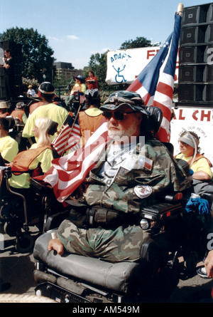 Uomo in una sedia a rotelle con una disabilità fisica (mancano gli arti inferiori) frequentando un Disability Advocacy evento. Foto Stock