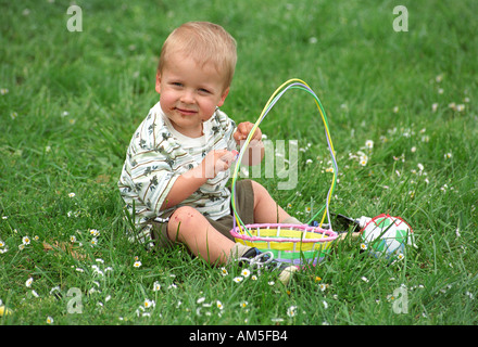 Ragazzo giovane gode di candy dal suo cesto di Pasqua Foto Stock