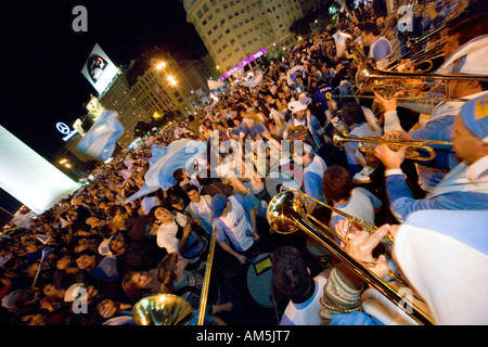 Musicisti suonano trombone e le trombe per un tifo e ballare la folla di tifosi di calcio al di sotto dell'Obelisco di Buenos Aires. Foto Stock