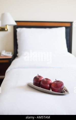 Tre mele in una piastra sul letto in una stanza di un hotel Foto Stock