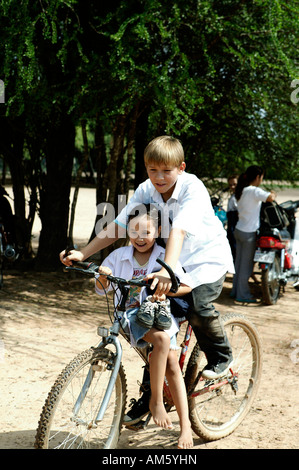 Fratello di prelevare la sua sorellina dalla scuola con la bicicletta, Loma Plata, Chaco, Paraguay, Sud America Foto Stock