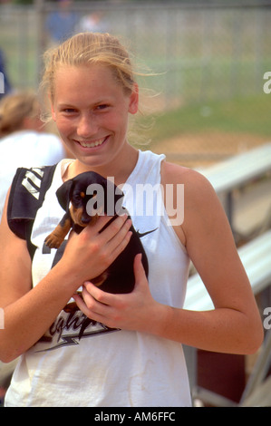 Fast pitch softball player età 18 tenendo il cucciolo di Dunning Park. St Paul Minnesota USA Foto Stock