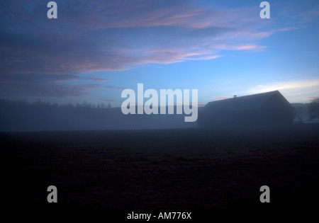 La nebbia e il tardo pomeriggio paesaggio di luce, con il campo e gli agricoltori house, un po' di mistero sentimento o emozione, nice le nuvole in cielo. Foto Stock