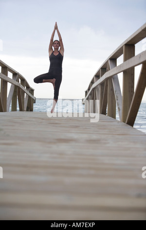 Giovane donna fare yoga posa ad albero Foto Stock