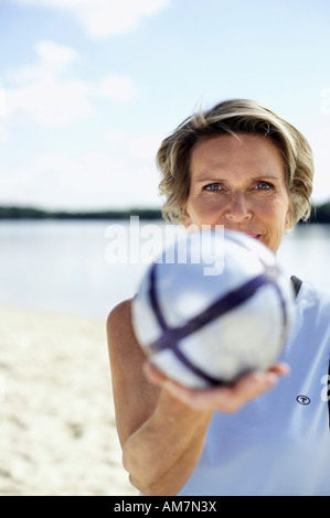 Bestager 60+ con pallavolo sulla spiaggia Foto Stock