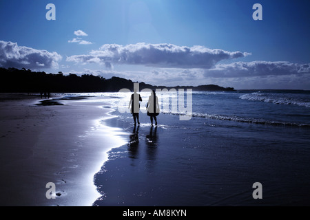 Un giovane a piedi lungo su di una spiaggia di sabbia in sunset Foto Stock