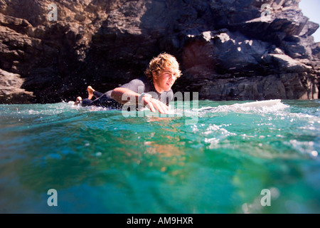 Uomo disteso sulla tavola da surf in acqua sorridente. Foto Stock