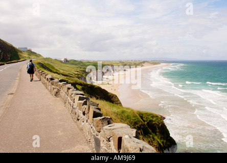 Irlanda. Walker su North Antrim Coast Road, Portrush. Attraversa East Strand presso le White Rocks e guarda oltre la città di Portrush Foto Stock
