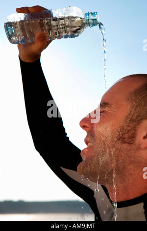 Uomo in wetsuit versare acqua sul suo volto. Foto Stock