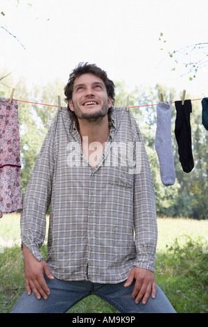 L'uomo appeso su stendibiancheria con clothespins sorridente. Foto Stock