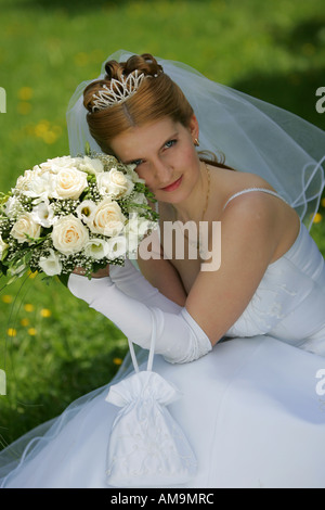 Un ritratto di una sposa in bianco di un abito da sposa con un bouquet. Foto Stock