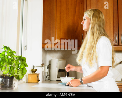 Donna in piedi con la tazza di tè in cucina. Foto Stock