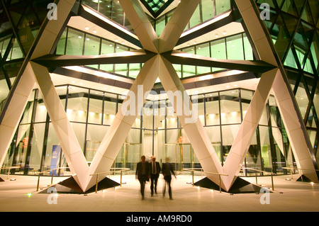 Ufficio i lavoratori che lasciano la Swiss Re Tower di notte Foto Stock