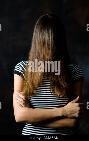 Giovane donna capelli che ricopre la faccia con le braccia incrociate Foto Stock