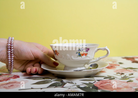 Una donna di mano che regge una tazza e piattino Foto Stock