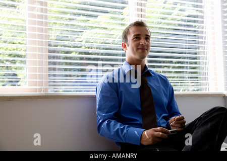 Un giovane imprenditore seduto da una finestra Foto Stock
