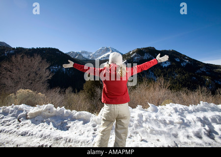 Una donna che guarda alle montagne con le braccia aperte Foto Stock