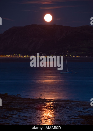 Luna si elevano al di sopra di MENAI stretto con la luna piena al di sopra di Tal y ventola da Beaumaris Anglesey North Wales UK Foto Stock