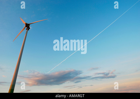 Una turbina eolica e un sentiero di vapore nel cielo Foto Stock