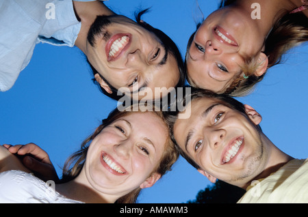 Quattro giovani in huddle, vista verso l'alto, ritratto Foto Stock