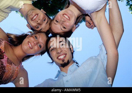 Quattro giovani in huddle, vista verso l'alto, ritratto Foto Stock