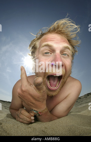 Crazy giovane uomo disteso sulla spiaggia, sole bruciare al suo orecchio Foto Stock