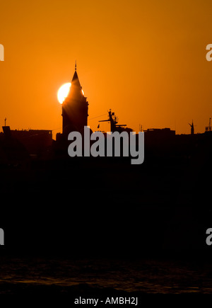 Sun impostazione sul Galata il sole tramonta in un cielo arancione facendo una silohette della Torre di Galata un nuovo quartiere di punto di riferimento Foto Stock