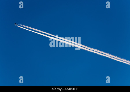 Getto di vapore aereo trail contro un cielo azzurro sopra l'aeroporto di Heathrow, fotografata da Twickenham, West London. Foto Stock