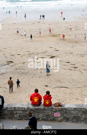 Una vista posteriore di due protezioni vita seduti sulla parete affacciata fistral beach in Cornovaglia Foto Stock