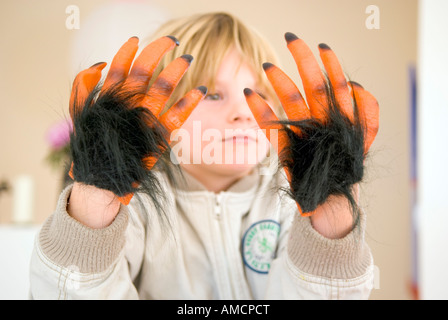 Ragazzino con una coppia di scherzo orange hairy monster le mani davanti al suo volto Foto Stock