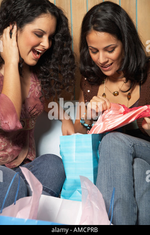 Due donne alla ricerca all'interno di borse per lo shopping Foto Stock