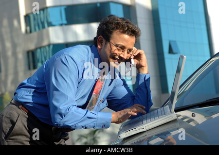 VEP72161 giovani indiani Executive con cravatta parlando al telefono cellulare e di lavoro sul computer Foto Stock