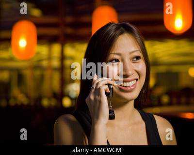 Donna che parla su un telefono cellulare all'aperto di notte sorridente Foto Stock