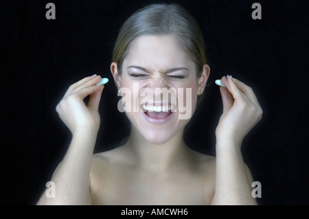 Donna mettendo i tappi per le orecchie Foto Stock