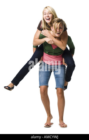 Due ragazze adolescenti ridendo e dando piggy back ride Foto Stock