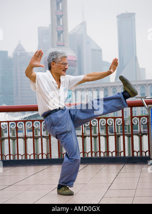 L'uomo facendo tai chi all'aperto con lo skyline della città in background Foto Stock