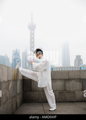 L'uomo facendo tai chi all'aperto con lo skyline della città in background Foto Stock