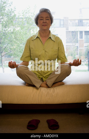 Donna matura seduta zampe trasversale in meditazione Foto Stock