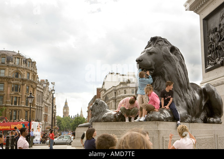 I turisti con Nelsons Column Lions in Trafalgar Square a Londra con il Big Ben in background Foto Stock