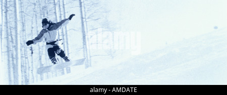 Snowboarder Jumping oltre la collina Foto Stock