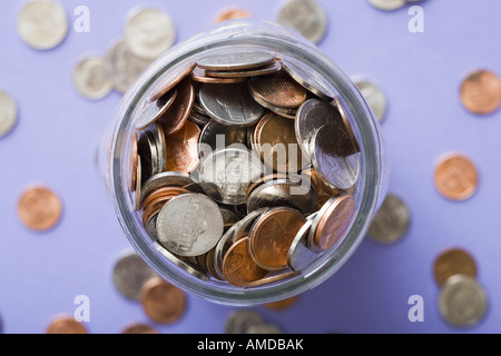 Vaso di vetro con delle monete in euro e monete sparse Foto Stock