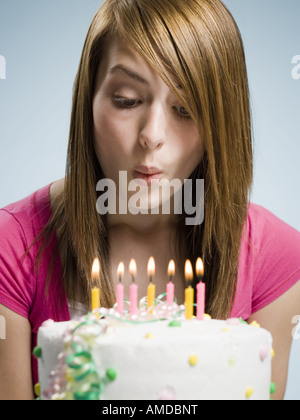 Donna soffiando fuori candele su una torta di compleanno Foto Stock