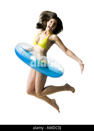 Donna in bikini con anello di nuoto intorno alla vita di salto e sorridente Foto Stock