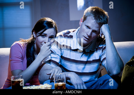 Paio di guardare la televisione con coppa di popcorn guardando triste Foto Stock