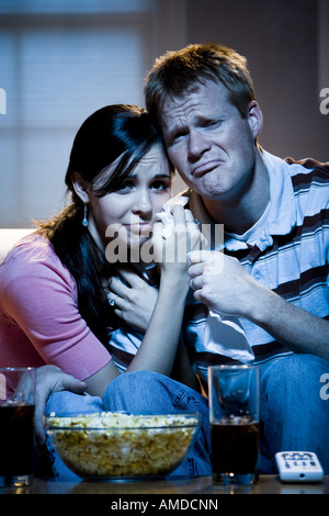 Paio di guardare la televisione con una ciotola di popcorn e pianto di tessuto Foto Stock